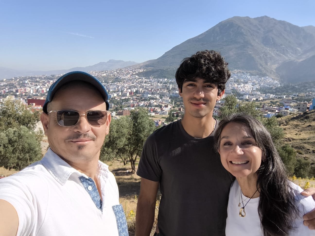Three travellers overlooking a Moroccan town and mountain landscape