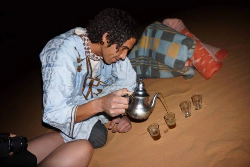Tea being poured beside a fire during a desert evening